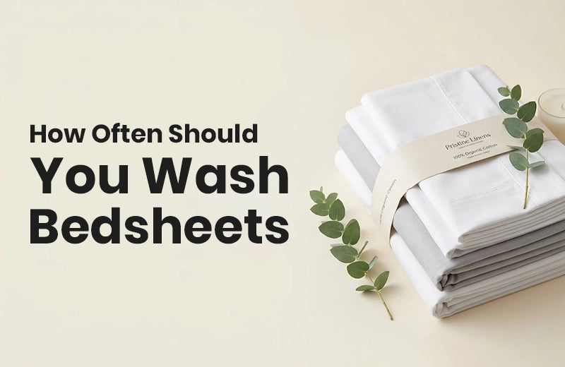 Folded white and grey cotton bedsheets with eucalyptus sprigs on a cream background